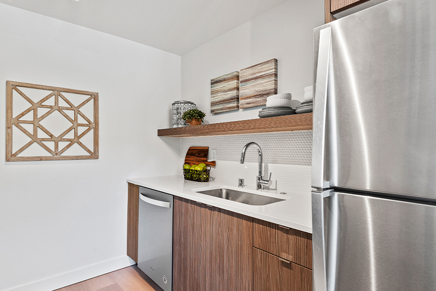 kitchen interior with floating shelves, stainless fridge, and granite countertops